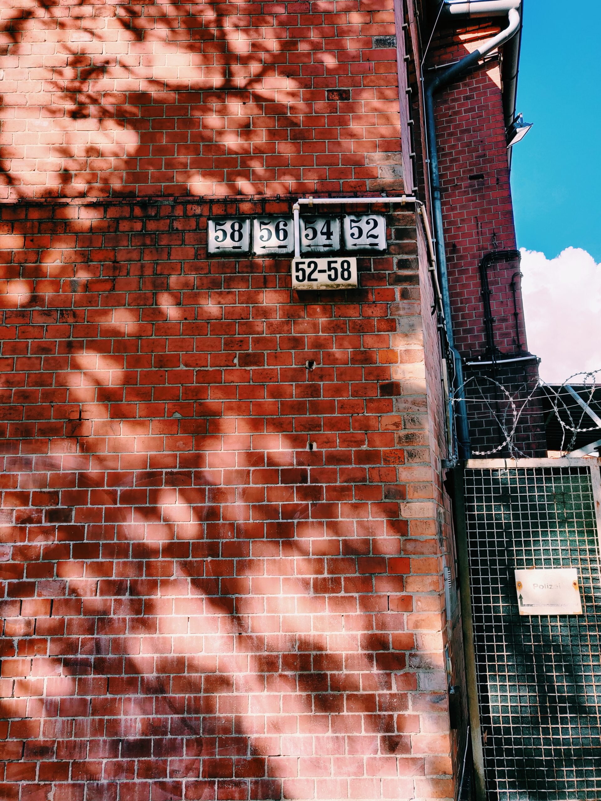House numbers 58, 56, 54, 52 as well as a sign "52-58" on a brick wall.
