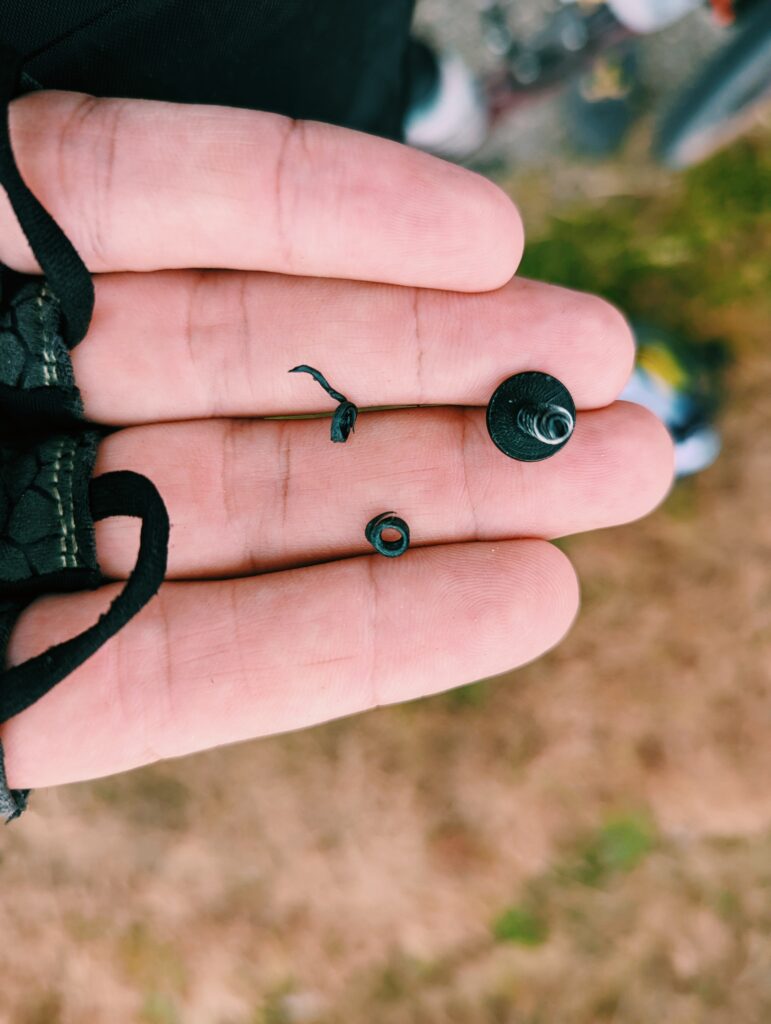 Hand holding a broken screw and broken of pieces of plastic