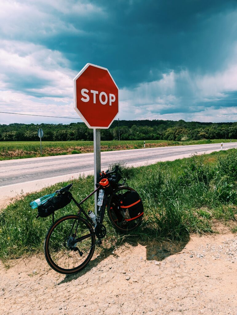 My bike propped up against a stop sign, dark rain clouds in the background