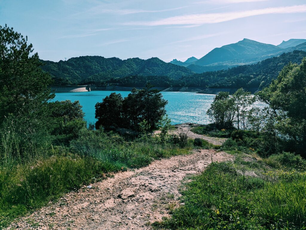 Panta de las Baells lake in the middleground, a small path in the foreground and some hilltops in the background