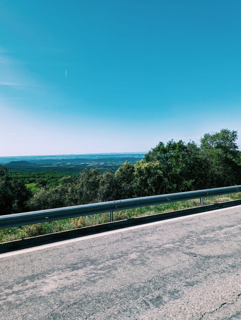 Tarmac and a guard railing in the forground. Flat lands below until the horizon. Clear blue skies.