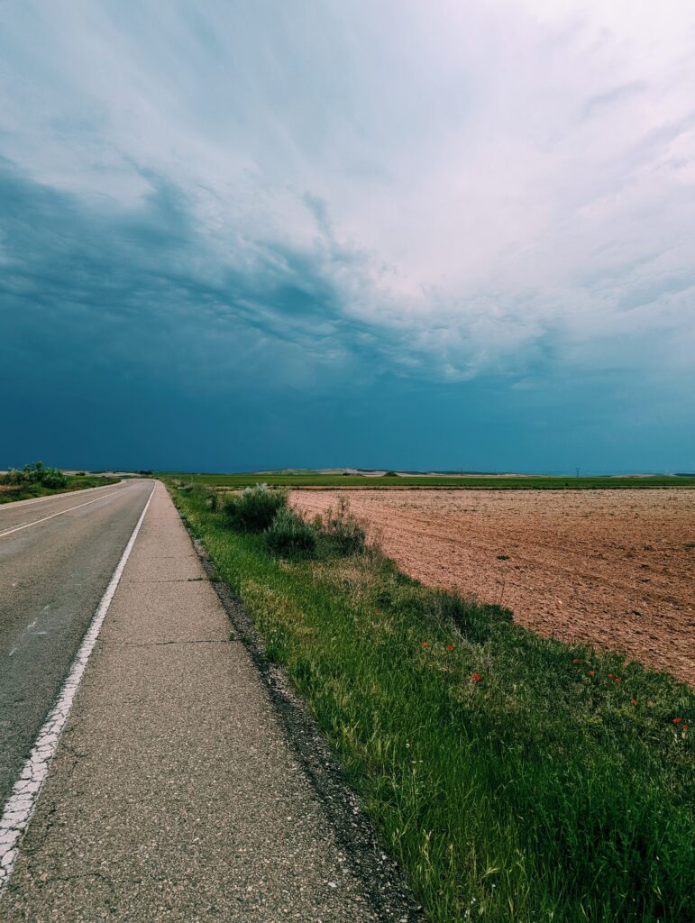 Straight road in the foreground going to the horizon dark clouds in the sky