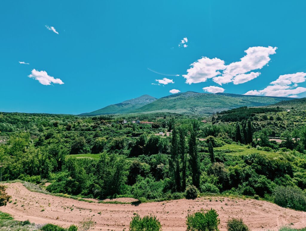 Moncayo in the background, blue skies with very few clouds, lush green bushes and fields in the foreground