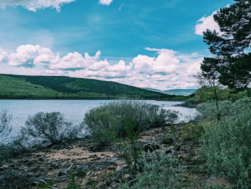 Embalse de Cuerda del Pozo lake with hills in the background and some clouds in the sky